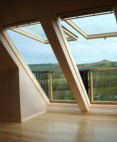 an empty room with large windows and wooden flooring, overlooking the rolling hills in the distance