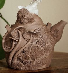 a ceramic teapot with flowers and leaves on it