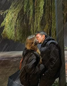 a man and woman kissing under an umbrella in the rain while it's raining