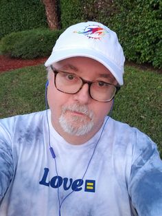 a man with glasses and a white hat is taking a selfie in the park