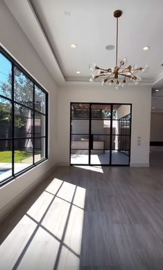 an empty room with large windows and a chandelier