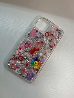 a cell phone case with flowers and hearts on the back is sitting on a table