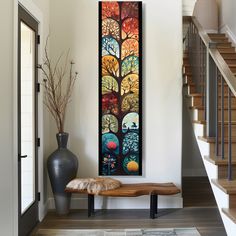 a painting hanging on the wall next to a wooden bench in front of a stair case