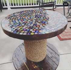 a round table made out of bottle caps on top of a wooden stand with rope