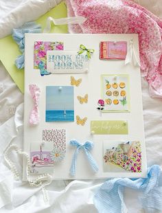 a white board covered in lots of different things on top of a bed next to a pink and blue blanket