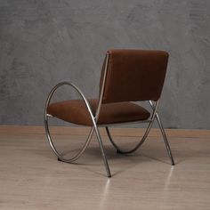 a chair that is sitting in the middle of a room with wood flooring and concrete walls