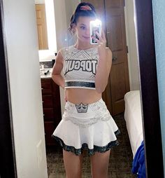 a woman taking a selfie in a mirror wearing a white top and black skirt