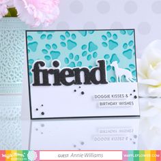 a card with the word friend on it and a vase full of flowers behind it