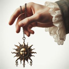 a woman's hand holding an antique sun pendant with a chain attached to it