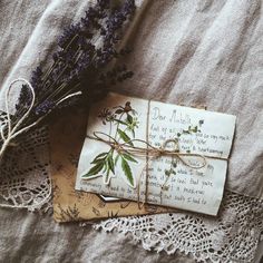 two envelopes with flowers tied to them on a lace doily next to a bouquet of wildflowers