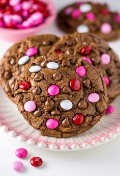 chocolate cookies with m & m candies on a paper plate next to pink and white candy