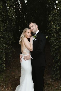 a bride and groom posing for a photo in front of some trees at their wedding