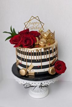 a black and white cake with red roses on the top is decorated with gold lettering