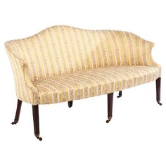 an upholstered bench with wooden legs and striped fabric on the armrests