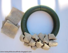 a green wreath with burlap and fabric pieces around it on a white surface