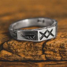 a silver ring with two crossed crosses on it sitting on top of a piece of wood