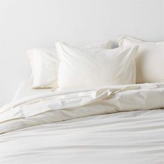 a bed with white sheets and pillows on it