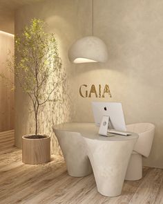 a white table with a laptop on it in front of a plant and potted tree