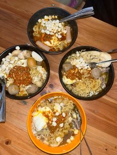 three bowls filled with food on top of a wooden table