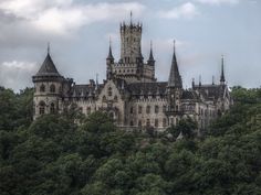 an old castle on top of a hill surrounded by trees