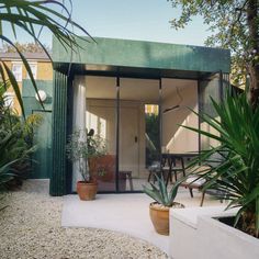 an outdoor room with potted plants and chairs