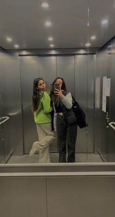 two women taking pictures in an elevator