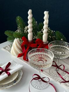 two wine glasses sitting next to each other on a table with candles and napkins