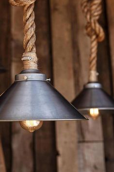 two metal lamps hanging from rope with light bulbs on them