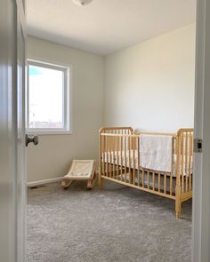 a baby's crib in the corner of a room with an open door