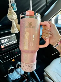 a person holding a pink cup in their hand while sitting in the backseat of a car