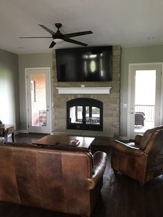 a living room with leather furniture and a flat screen tv mounted above the fire place