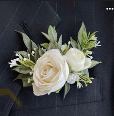 a boutonniere with white flowers and greenery on it's lapel