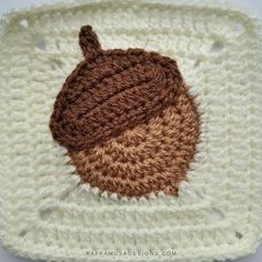 a crocheted square with a brown and white acorn on the center, in front of a white background