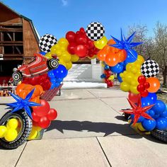 an arch made out of balloons with cars and stars on the front, along with other decorations