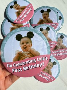 a person holding some pink and white buttons with mickey mouse on it's face