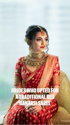 a woman in a red and gold sari sits on a chair with her hands clasped to her chest