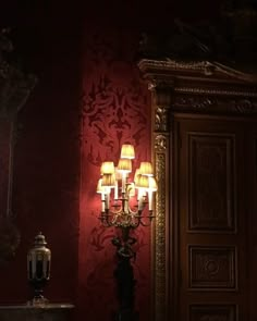 a chandelier in a dark room with red wallpaper and gold trimming