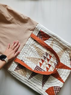 a woman is holding onto a quilt on the floor with her hand over it's shoulder