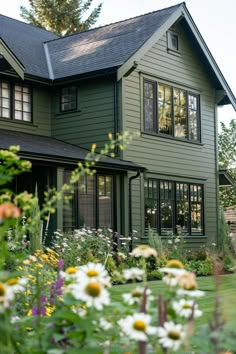 a green house with lots of flowers in the front yard