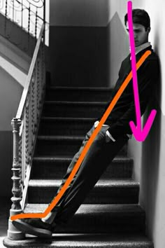 a man sitting on top of a stair case next to a hand rail with an orange arrow pointing up