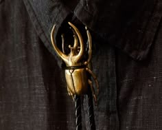 "Hold up the heavens with this Atlas Beetle bolo tie. This adjustable brass bolo tie* comes with a black braided cord with goldtone tips. Wear it for any occasion, formal or casual, and you are sure to receive compliments on this unusual piece. The Atlas beetle--named after Atlas the giant in Greek mythology that supported the skies--is found in Southeast Asia. Males have three prominent horns that are used to fight each other to gain mating favor. The males are larger than females and range fro Atlas Beetle, Bug Fashion, Nature Accessories, Male Gifts, Tie Jewelry, Gift For Groomsmen, Gold Tie, Bolo Ties, Bolo Tie