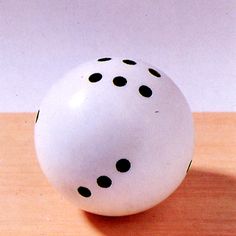 a white ball with black dots sitting on top of a wooden table