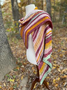 a knitted shawl draped over a white mannequin headpiece in the woods