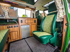 the interior of a vehicle with green leather seats and wood paneling on the walls