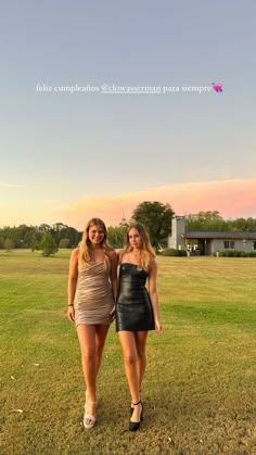 two women standing next to each other in the grass