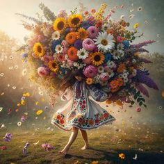 a woman carrying a large bouquet of flowers on her head in the middle of a field