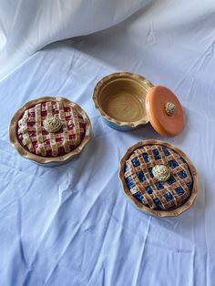 "Ceramic jars sculpted to look like pies. Comes in three \"flavors\" - Blueberry, Cherry and Pumpkin.  Blueberry Pie Jar features a gray \"aluminum pie tin\" base with a wavy \"pie crust\", the jar lid features blue \"berries\", a lattice \"crust\" and a \"whipped cream\"handle.  Cherry Pie Jar features a gray \"aluminum pie tin\" base with a wavy \"pie crust\", the jar lid features red \"berries\", a lattice \"crust\" and a \"whipped cream\" handle.  Pumpkin Pie Jar features a gray \"aluminum p Memory Box Ceramics, Clay Containers With Lids Ideas, Clay Jars With Lids, Clay Containers With Lids, Ceramic Lidded Jars, Pie Ceramic, Food Ceramics, Pie Jars, Pumpkin Blueberry