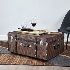 an old trunk sitting on top of a rug next to a chair and glass of wine