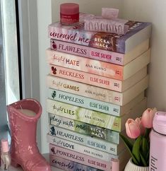 a stack of books sitting on top of a table next to a vase with flowers