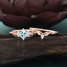 an engagement ring with a blue topazte surrounded by white diamonds on a piece of wood